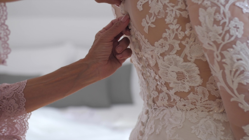Mother buttons wedding dress of her daughter, side closeup slow motion shot Royalty-Free Stock Footage #1054005449