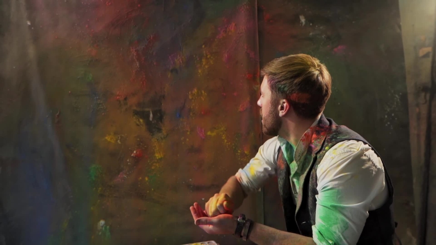 artist throws colored dry paint on the canvas