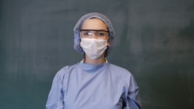 Female Doctor or Nurse Wearing Scrubs and Protective Mask and Goggles Banner. Smiling doctor look at the camera. 4K slow motion video.