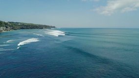 Drone flight over azure blue ocean with barreling waves on sunny day. Aerial video of ocean waves surface at summer. Blue ocean water texture. Nature, view from above.