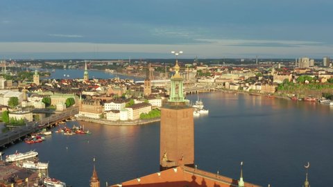 Stockholm Sweden City Hall golden crowns and old town and royal palace in background. Rotating aerial drone shot parallax effect. Magical day light in swedish capital city