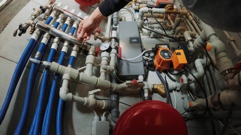 Professional plumber. Plumbing repair service. Repairman fixing a gas water heater with a screwdriver. Worker hands fixing heating system