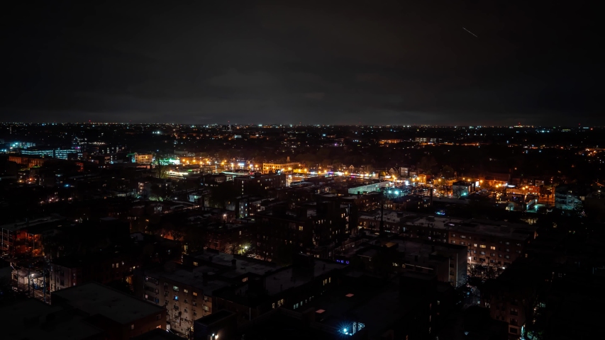 Dramatic aerial nighttime weather time lapse as an intense storm system and clouds move over the city and residential neighborhoods with Strikes of Lightning flashing and lighting up the night.