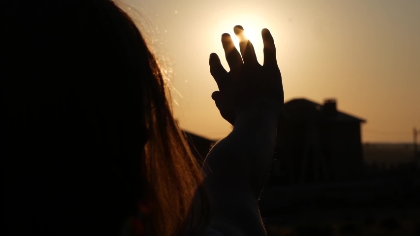 Close-up of a woman's hand in silhouette touching the sun rays in a field | Shutterstock HD Video #1054035983