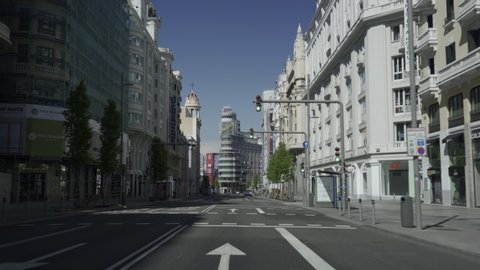 MADRID, SPAIN - APRIL 12TH 2020. Drive-through shot of daunting empty Gran Via, one of the most iconic, famous and crowdest avenues in downtown Madrid, during coronavirus or covid pandemic lockdown