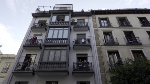MADRID, SPAIN - APRIL 11TH 2020. Traveling shot of residents of several apartment blocks in Madrid city center dancing and partying at their balconies during coronavirus or covid pandemic lockdown