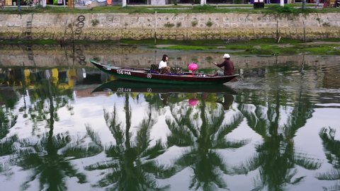 Hoi An, Vietnam - june 05, 2020 : Vietnamese boatman rides a girl on a wooden boat in the river along the promenade in Hoi An Old Town, Vietnam