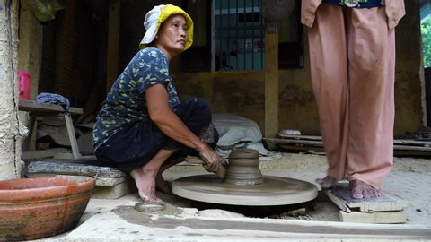 Hoi An, Vietnam - june 05, 2020 : Close-up of a woman potters rotate a wheel with her foot and making a beautiful clay pot with her hands at pottery manufacture in the Old Town Hoi An, Vietnam