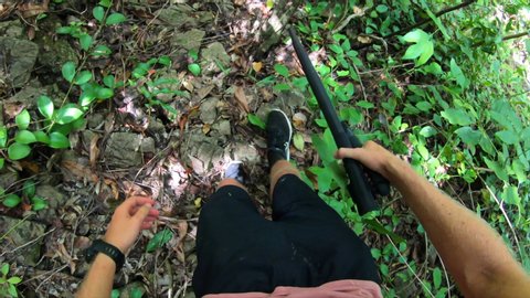 POV shot of tourist cutting plants with machete while hiking in jungle on sunny day - Wakatobi Regency, Indonesia