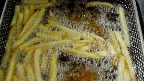 French fries in the deep fryer, in a fast food restaurant, cooking potato, crispy fries, Junk food concept, top view Close up.