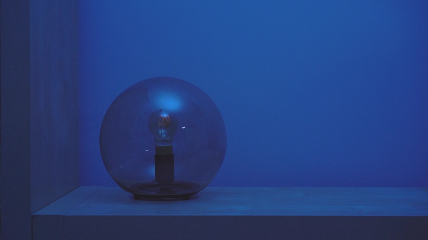 Faceless person turning on and after few seconds turning off with her finger creative table lamp with dark glass dome on in blue room in evening Royalty-Free Stock Footage #1054053587