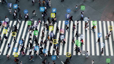 Japan, June 10, 2020: Crowded people using famous social media applications. Aerial view of pedestrians walk at Shibuya Crossing. Social media applications technology concept.