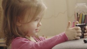 Beautiful little girl watching videos of herself on a smartphone