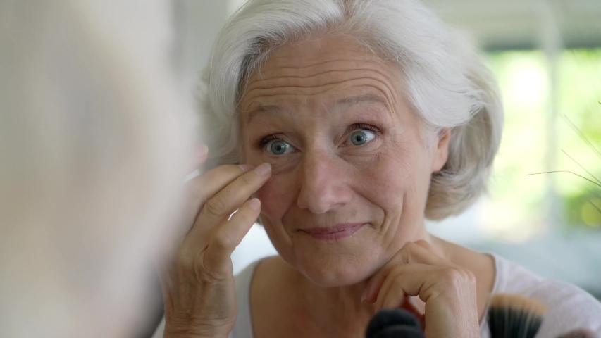 Portrait of senior woman taking care of her skin, looking at mirror Royalty-Free Stock Footage #1054056125