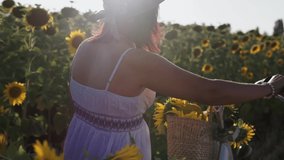 A woman in a hat and a white dress with a bicycle walks through the pollen with sunflowers