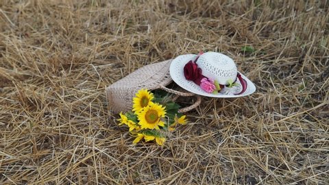 Still life of hats and baskets with sunflowers on a mowed field
