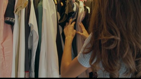 Young woman choosing which clothes to wear from her wardrobe