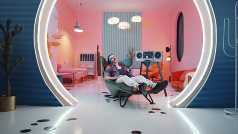 Zoom in shot of stylish man with mustache and bowl haircut chilling on art deco armchair and showing vogue hands performance for camera in vintage studio with retro cassette player and pink light