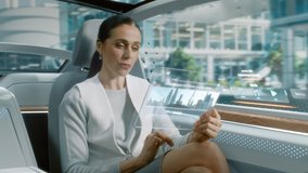 Futuristic Concept: Attractive Stylish Female Reading News on a Futuristic Transparent Tablet Computer with Augmented Reality Interface while Sitting on a Backseat of Autonomous Self-Driving Car - Powered by Shutterstock - Get 15% off with code: PIKWIZARD15