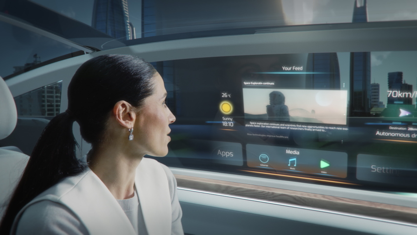Futuristic Concept: Zoom Out View of an Attractive Female Reading the News on a Futuristic Augmented Reality Interface while Talking to Another Passenger. Riding in an Autonomous Self-Driving Car Royalty-Free Stock Footage #1054062338