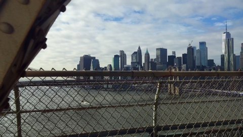 Glimpse of Manhattan and the Brooklyn Bridge interspersed with the passage of metal beams from the subway window as it crosses the East River on a bridge in the direction of Brooklyn District