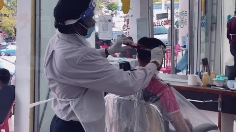 Melaka/Malaysia - June 10,2020 : 4K real time footage of indian barbershop operating with new standard operating procedure. Barber wearing PPE. This is a new norm. Good for business documentary
