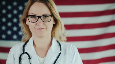 Attractive female doctor looks into camera amid US flag