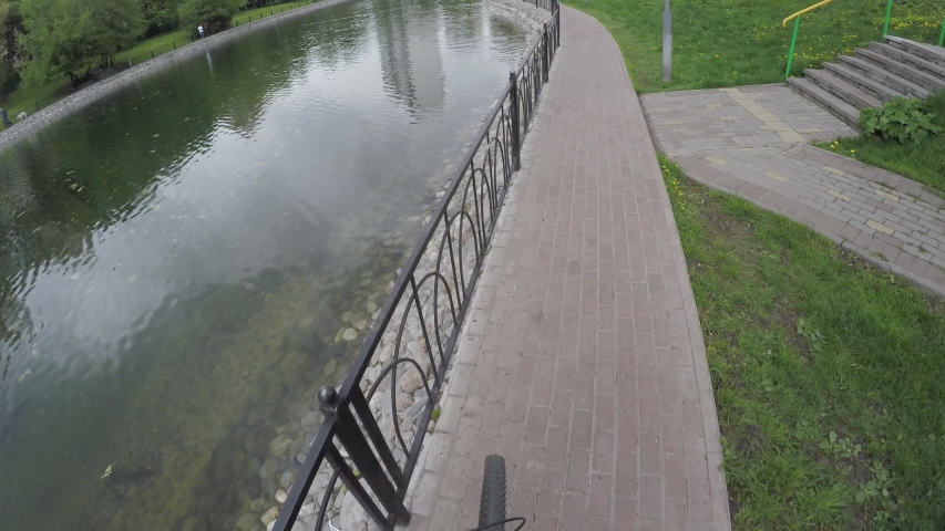 FPV of riding bike near pond in park