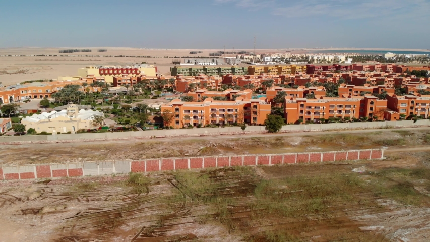 Evening flying from above over the hotel and the desert near Hurghada. Top view of residential buildings, swimming pools for tourists. Beautiful territory in the middle of the desert. Oasis.