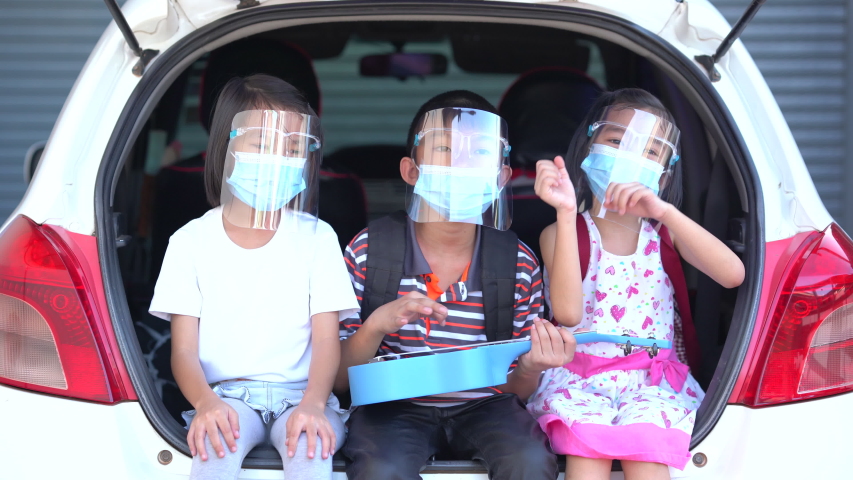 Trip coronavirus protect and social distancing concept, kids playing and singing song on car at home, funny on outdoor stay at home and wearing mask and face shield for protect coronavirus, child thai Royalty-Free Stock Footage #1054078052