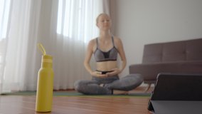 Focus is on the tablet. Fitness woman exercising on the floor at home and watching fitness videos in a tablet. People do sports online because of the coronovirus