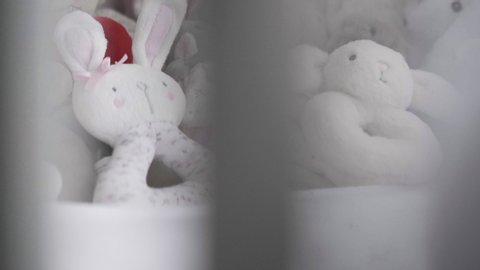 Close up of cuddly soft toys in newborn baby girl's crib.