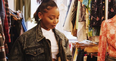 young black woman in a vintage clothes shop, trying on denim jacket with fake fur lining