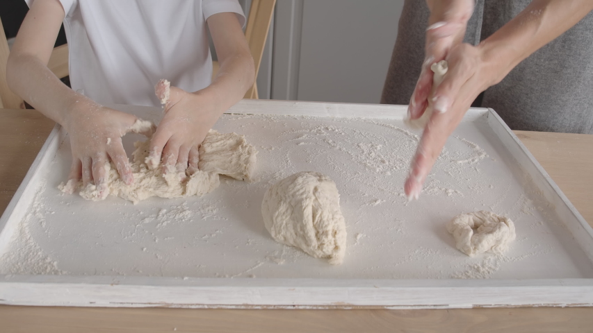 Little boy mixing dough with her mother at home. Happy family kitchen baking.