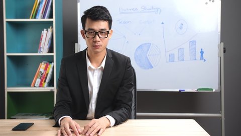Asian Businessman Looking At Camera Talking About Business Plan
