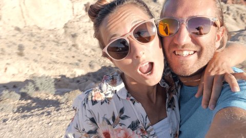 Couple traveling takes selfie picture on rock formation settings. Young couple taking selfies in wester USA. People travel concept.