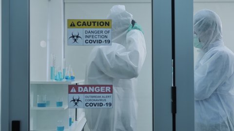 Two asian scientist is wearing Personal Protective Equipment (PPE) in laboratory. Protection coronavirus or covid19 and Medical experiment concept. Slow motion Dolly slider shot