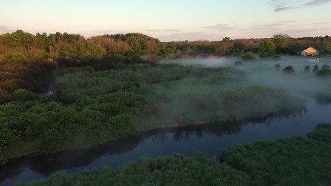 Aerial view of american countryside in the summertime. Sunrise, dawn, misty early morning. North american landscape,  Beautiful nature of Midwest. Fog over the river, soft  sunlight on the trees. 