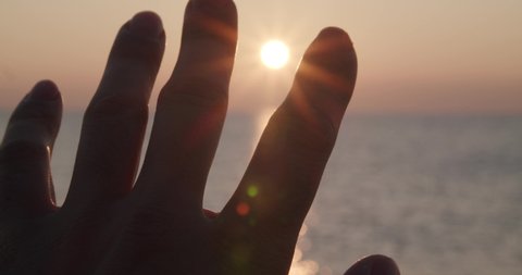 Close up focused foreground hand reaching sunrise, bokeh sea horizon, Almeria, Spain