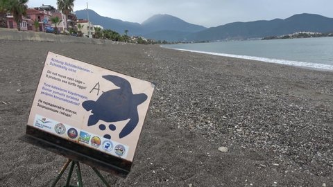 Calis beach, Fethiye, Turkey - 1st of June 2020: 4K First post-quarantine day - Sign plate with international writings on the turtle nest cage at the abandoned beach

