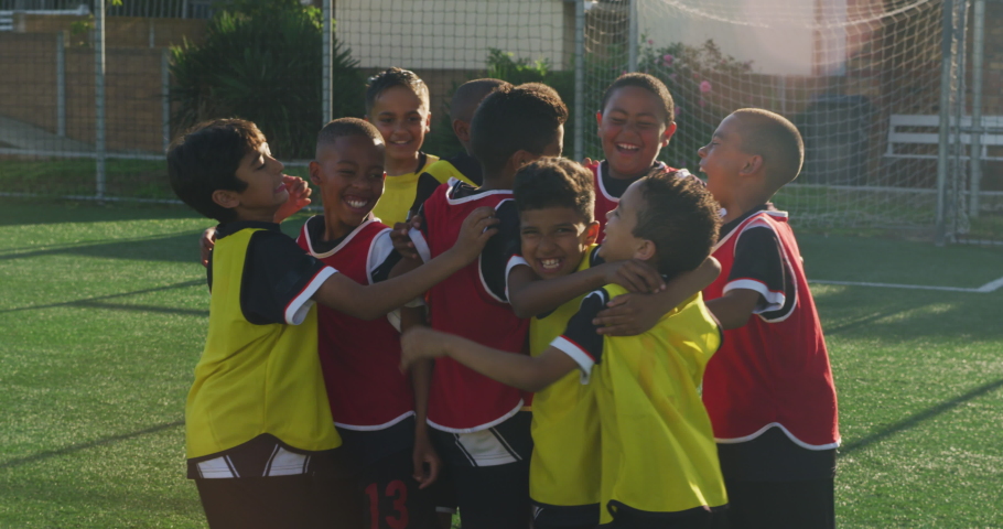 Multi-ethnic group of two children teams playing soccer on a green football pitch, on a sunny day, celebrating a goal, hugging and jumping Royalty-Free Stock Footage #1054102610