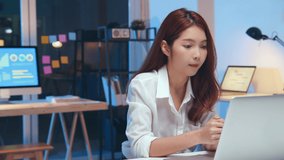 Young Asian business woman on video conference call, using laptop computer work late night. Remote meeting, work at home, internet technology, Covid-19 quarantine lockdown new normal lifestyle concept