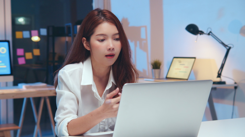 Young Asian business woman on video conference call, using laptop computer work late night. Remote meeting, work at home, internet technology, Covid-19 quarantine lockdown new normal lifestyle concept Royalty-Free Stock Footage #1054104248