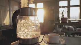 A transparent kettle of water boils against the background of the sunset shining through the window. The concept of coffee break and end of the working day. - Powered by Shutterstock - Get 15% off with code: PIKWIZARD15