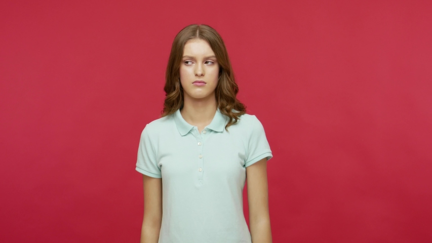 Don't want to watch! Displeased young brunette woman in polo t-shirt covering eyes and gesturing stop, confused and shy to look at shameful content. indoor studio shot isolated on red background Royalty-Free Stock Footage #1054106699