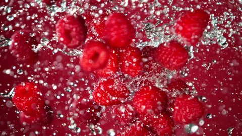 Super Slow Motion Shot of Flying and Splashing Fresh Raspberries on Red Gradient Background at 1000fps.