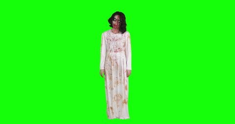 Creepy zombie woman with wounded face standing in the studio. Shot in 4k resolution with green screen background