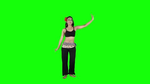 Full length view of pretty belly dancer shaking her hip while performing in the studio with green screen background
