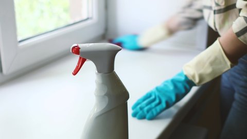 Cleaning service. young woman in gloves wipes the dust off the windowsill with a disinfectant foam with a rag at home, disinfection and house cleaning