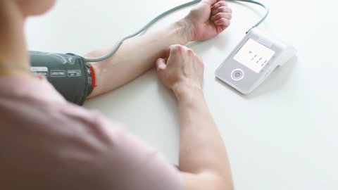 Woman hand and white electric tonometer on table for measuring blood pressure Healthy concept. Measurement of pressure and pulse. Hypertension and hypotension